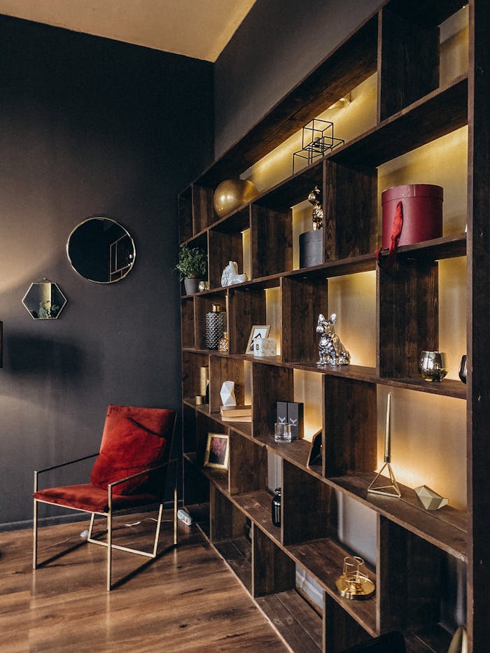 Stylish modern interior with illuminated wooden shelves and a red chair.